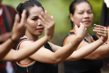 Kontum bölgesindeki Bahnar etnik köyünde geleneksel tören. Geleneksel elbiseli genç kadınlar dans gösterisi yapıyorlar. Kontum. Vietnam.