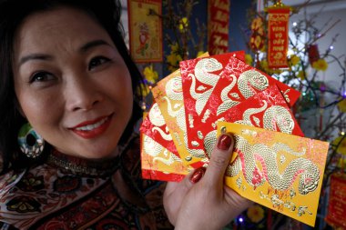 Çin ve Vietnam 'ın yeni yıl kutlamaları için kırmızı zarflı Asyalı kadın. Kırmızı renk iyi şansın sembolüdür. Yılan Yılı.