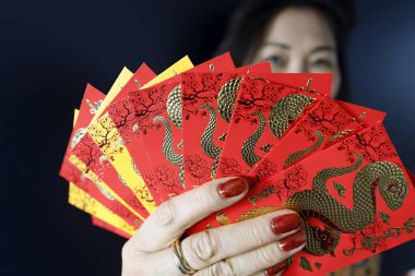 Çin ve Vietnam 'ın yeni yıl kutlamaları için kırmızı zarflı Asyalı kadın. Kırmızı renk iyi şansın sembolüdür. Yılan Yılı.