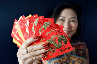 Çin ve Vietnam 'ın yeni yıl kutlamaları için kırmızı zarflı Asyalı kadın. Kırmızı renk iyi şansın sembolüdür. Yılan Yılı.