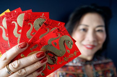 Çin ve Vietnam 'ın yeni yıl kutlamaları için kırmızı zarflı Asyalı kadın. Kırmızı renk iyi şansın sembolüdür. Yılan Yılı.