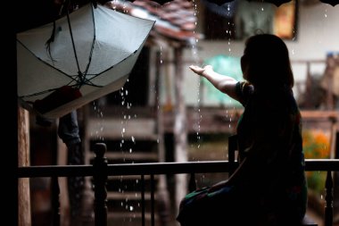 Asya 'da yağmur mevsimi ya da muson mevsimi. Yağmur sırasında evde kalan bir kadın. Kontum. Vietnam.