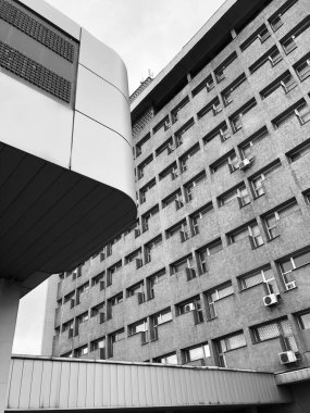 Çok katlı bir ofis tuğlasının fotoğrafı. Tepeden tırnağa. Siyah ve beyaz renkte birçok penceresi var.