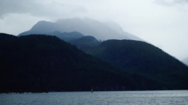 Arkasında dağ olan büyük bir su kütlesi.