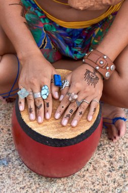 Girl's hands on bright drum, rings, mehendi, ethnic photoshooting.