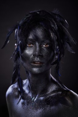 beautiful woman, black body over dark background, glitters and feathers