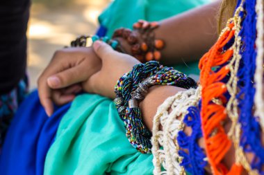 Parlak bilezikler, mavi turuncu elbise ile eller