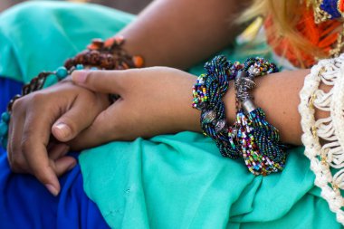 Parlak bilezikler, mavi turuncu elbise ile eller