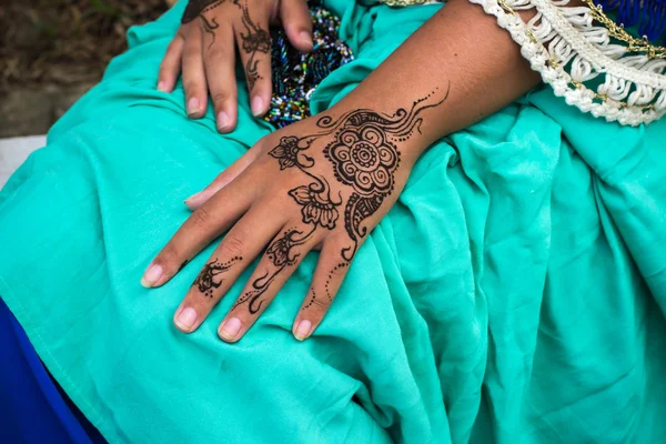 Vrouwelijke handen met henna tattoo mehndi op lichte blauwe jurk Stockfoto