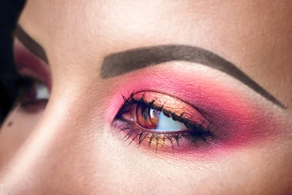 Elegance close-up of female eye with pink and gold eyeshadow. Macro shot of beautiful womans face part. Wellness, cosmetics and make-up. — Stock Photo, Image