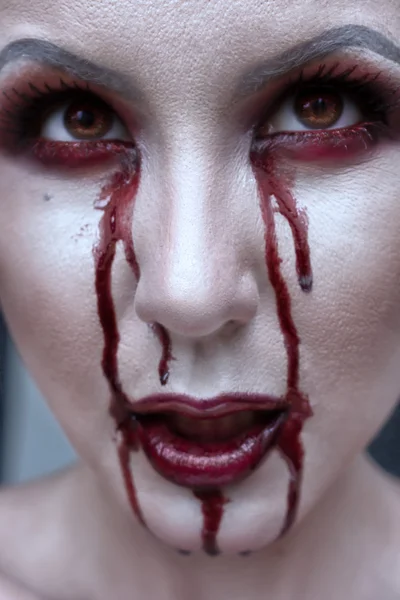 Schöne Vampirfrau, rote Lippen und blutüberströmte Augen in Großaufnahme. Halloween oder Horror-Thema. — Stockfoto