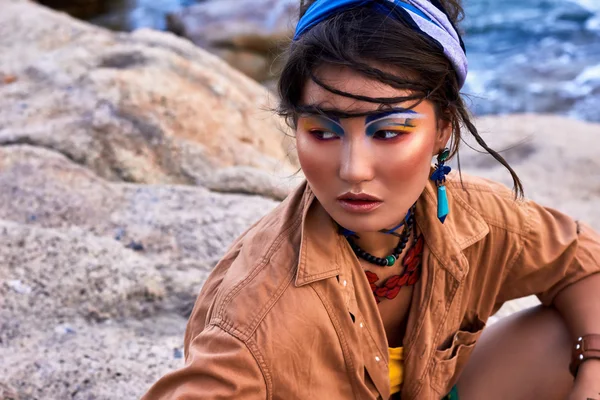 Asian woman, bright makeup, boho style, near sea, on mountain.