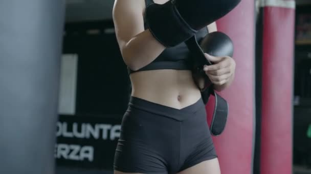 Bella donna atletica che allena la boxe in palestra, indossando guanti. — Video Stock