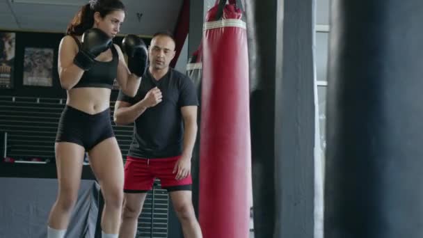 Krásná žena box bojová taška se sportovním trenérem dohromady. Dívka boxer cvičení box punč s osobní trenér. — Stock video