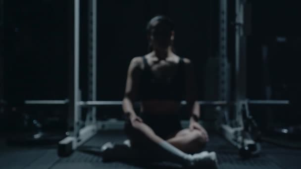 Αθλητική Καυκάσια γυναίκα κάθεται μόνη της μετά την καταμέτρηση στο σκοτεινό γυμναστήριο. — Αρχείο Βίντεο