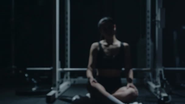 Deportiva mujer caucásica sentada sola después del workount en el gimnasio oscuro. — Vídeos de Stock