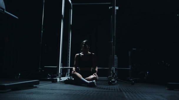 Sporty Caucasian woman sitting alone after workount in the dark gym. — ストック動画