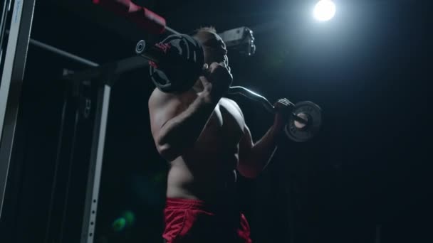 Joven deportista levantando pesadas pesas. Entrenamiento duro de deportista profesional, fondo oscuro. — Vídeos de Stock