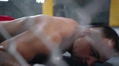 MMA fighter is falling on the floor after being hit and gets up quickly to continue the fight.