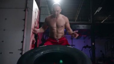 Bir spor salonu, sağlıklı bir yaşam tarzı ve fitness kavramı düşük açılı görünümünde büyük kauçuk lastik kaldırma dışarı çalışma crossfit egzersiz yapan uygun kaslı erkek