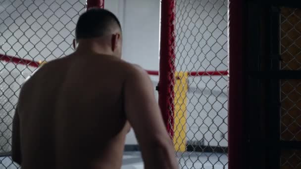 Muskulös MMA fighter går in i octagon bur och stänga den. — Stockvideo