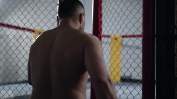 М'язовий боєць MMA входить у клітку восьмикутника і закриває її.. — стокове відео