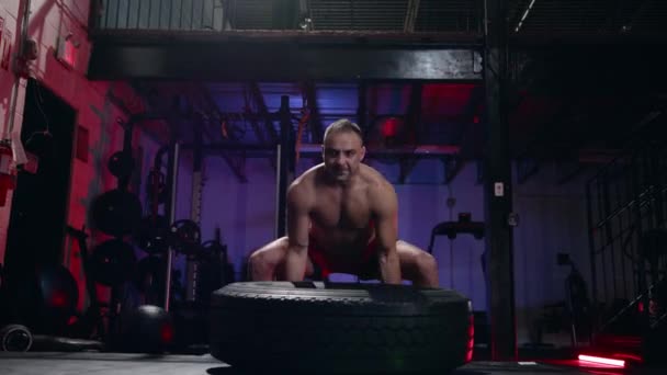 Fit muskulöser Mann bei Crossfit-Übungen beim Heben eines großen Gummireifens in einem Fitnessstudio, niedriger Blickwinkel in einem gesunden Lebensstil und Fitnesskonzept — Stockvideo