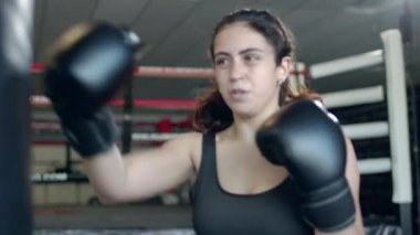 Boxing, woman fighter trains her punches, beats a punching bag, training day in the boxing gym, strength fit body, the girl strikes fast.