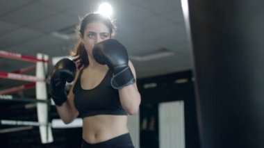 Boxing, woman fighter trains her punches, beats a punching bag, training day in the boxing gym, strength fit body, the girl strikes fast.