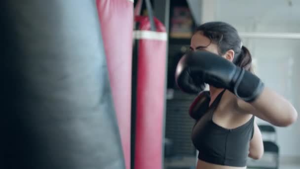 Boxning, kvinna fighter tränar sina slag, slår en slagsäck, träningsdag i boxning gym, styrka passform kropp, slår flickan snabbt. — Stockvideo