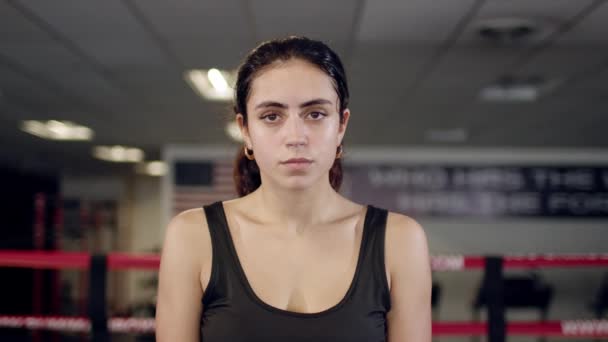Portrét krásné mladé unavené a zpocené ženy boxer otáčení tváří v tvář fotoaparátu s vážným pohledem na tmavý prsten. — Stock video