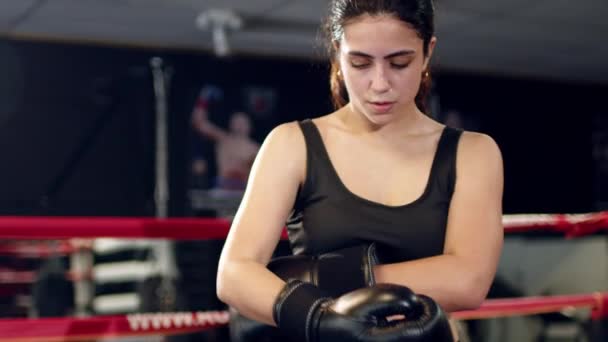 Mujer luchadora se quita los guantes de boxeo después del entrenamiento, día de entrenamiento en el gimnasio de boxeo y los deja caer en el ring. — Vídeos de Stock