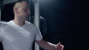 Young sportsman lifting heavy barbell. Hard training of professional sportsman, dark background.