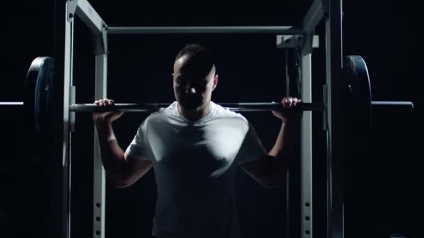 Pemuda olahragawan mengangkat barbel berat. Pelatihan keras olahragawan profesional, latar belakang gelap. — Stok Video