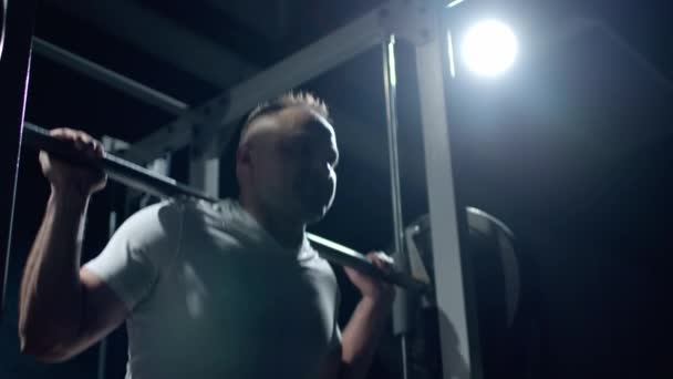 Young sportsman lifting heavy barbell. Hard training of professional sportsman, dark background. — Video