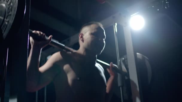 Joven deportista levantando pesadas pesas. Entrenamiento duro de deportista profesional, fondo oscuro. — Vídeos de Stock