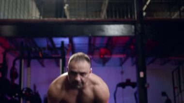 Bir spor salonu, sağlıklı bir yaşam tarzı ve fitness kavramı düşük açılı görünümünde büyük kauçuk lastik kaldırma dışarı çalışma crossfit egzersiz yapan uygun kaslı erkek