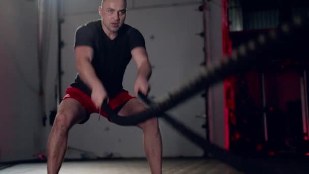 Упорный человек делает упражнения с боевой веревкой, беспощадно эффективные тренировки. — стоковое видео