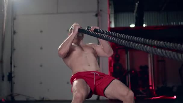 Assertive man doing exercises with battle rope, ruthlessly effective workout. — Stock Video