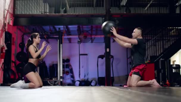 Atlet muda wanita bekerja di luar pada abs dengan pelatih laki-laki profesional, melemparkan bola cross fit di modern gym. — Stok Video