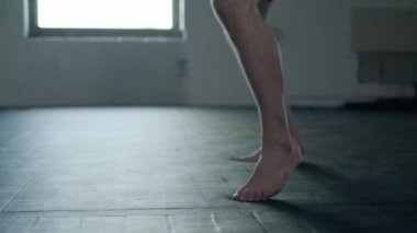Caucasian handsome man wearing boxing gloves punching ahead on sandbag in the dark room.