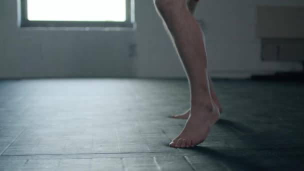 Hvid flot mand iført boksehandsker stansning fremad på sandsæk i det mørke rum. – Stock-video