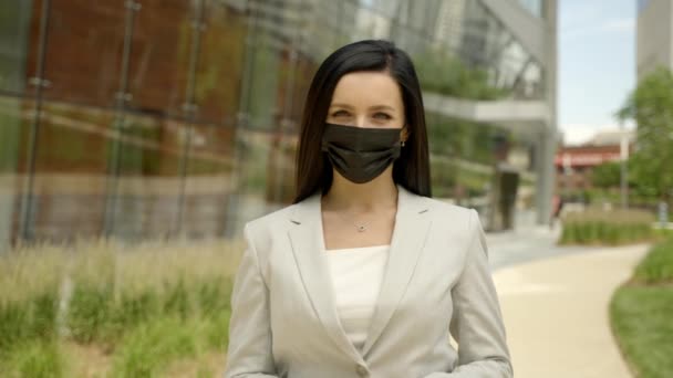 Cheerful brunette woman standing on street near modern office building and dropping off medical mask virus protection. — Stock Video