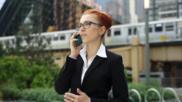 Giovane donna d'affari con i capelli rossi zenzero parlando sul telefono cellulare in città. — Video Stock