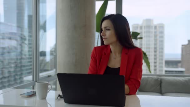 Triste mujer de negocios está sentado en la oficina moderna por la ventana panorámica con vista a la ciudad y mirando a la ventana. — Vídeos de Stock