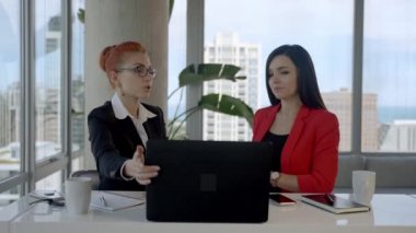 Two business woman working together in office with reports and taking a break for lunch.