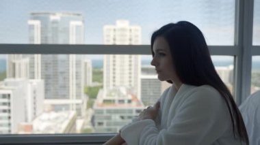 Side view of a sad woman sitting in the room embraces laps feels unhappy.