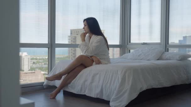 Side view of a sad woman sitting in the room embraces laps feels unhappy. — Stok video