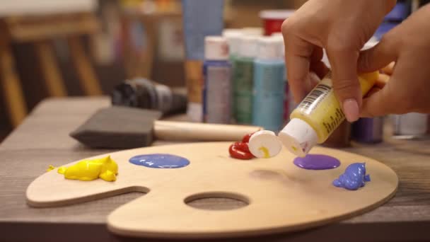 Mujer artista está exprimiendo pintura al óleo de un tubo en una paleta. — Vídeos de Stock