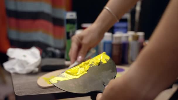 Woman artist is smearing yellow oil paint and paint scrapper. — Stock video